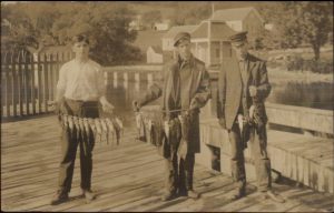 Old postcard of Meredith New Hampshire's dock and fishing trophies. The bait must have been good.